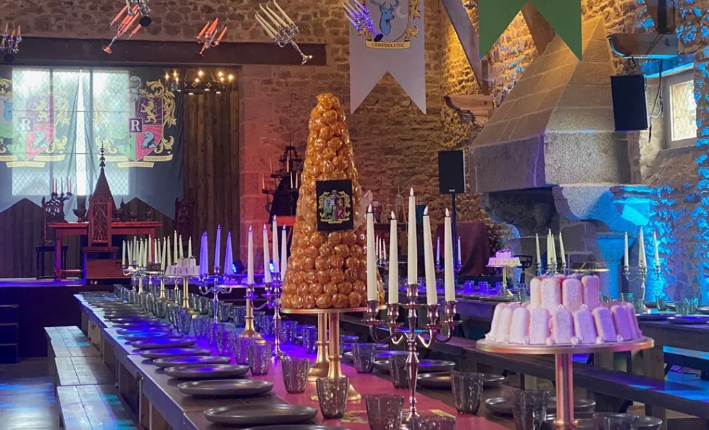 Imagen del salón de banquetes, con un magnífico pastel escalonado, candelabros antiguos, de la nueva escuela de magia - Le Rocher Portail.