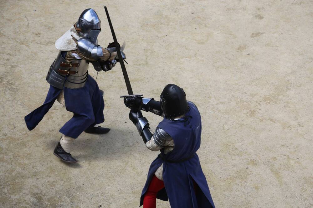 Photo de chevaliers se livrant un combat à l'épée dans une cour